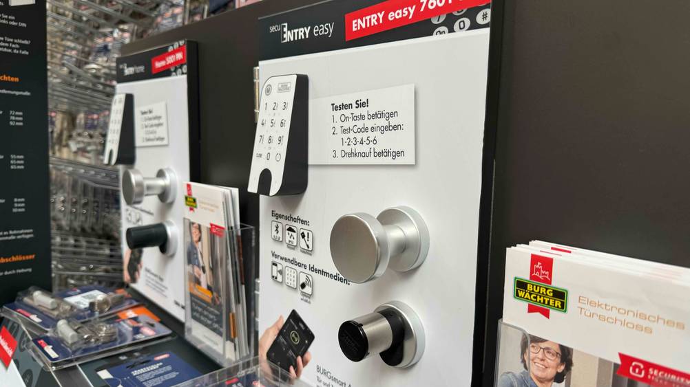 Smartes Türschloss getestet: Ein Gerät von schräg seitlich an einer Infotafel montiert.