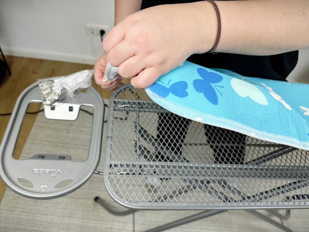 Der Bügeltischbezug wird über die Spitze des Bügelbretts gezogen. Das Muster ist sichtbar.