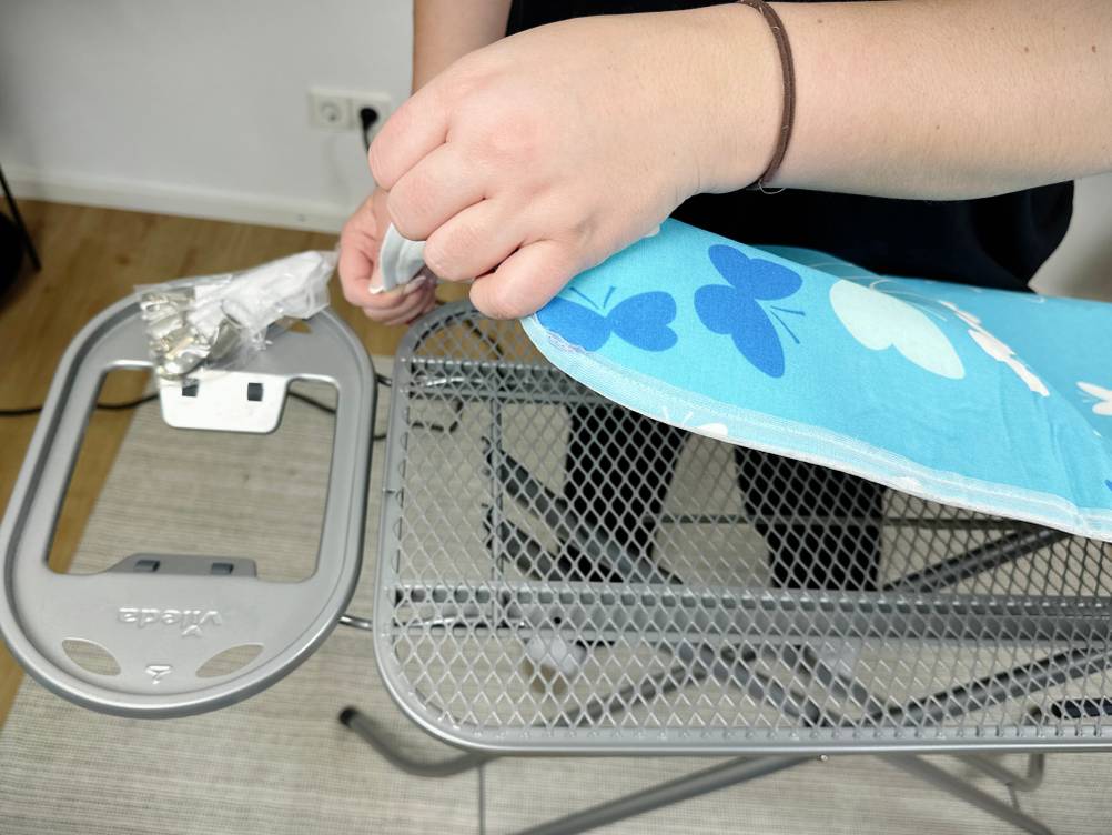 Der Bügeltischbezug wird über die Spitze des Bügelbretts gezogen. Das Muster ist sichtbar.