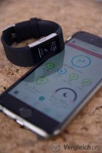 Fitness-Armband im Test. Fitness-Armband liegt neben einem Smartphone mit der dazugehörigen Fitness-App