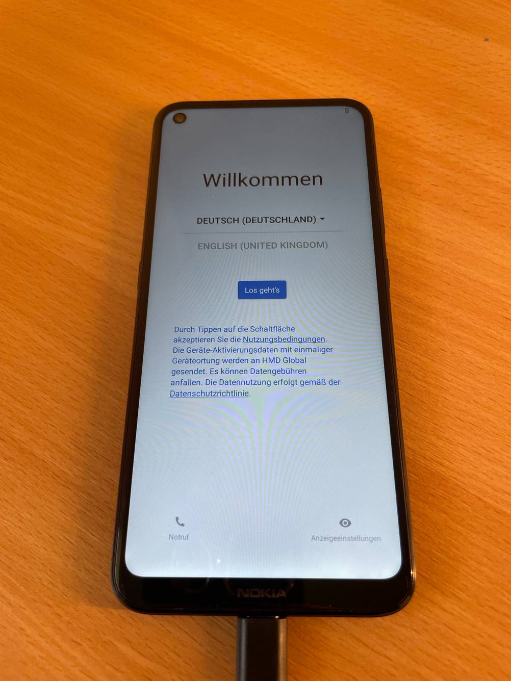Ein getestetes Smartphone bis 300 Euro angeschalten auf einer Holzfläche.