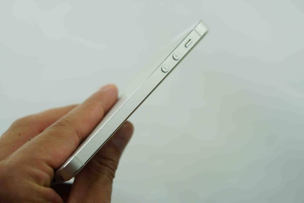 Seitenansicht eines getesteten Smartphones bis 200 Euro mit Fokus auf die Bedienelemente, von einer Hand vor eine helle Wand gehalten.