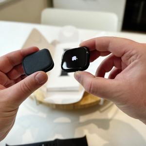 Die Person hält das Gehäuse der Apple Watch Series 11 in ihrer linken Hand und das eigentliche Gehäuse mit dem auf dem Always-on-Display dargestellten Apple-Logo in ihrer rechten Hand.