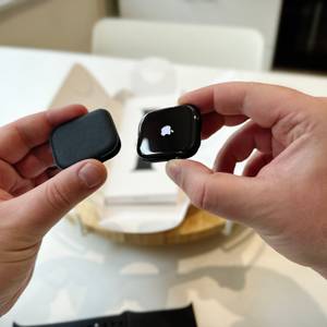 Die Person hält das Gehäuse der Apple Watch Series 11 in ihrer linken Hand und das eigentliche Gehäuse mit dem auf dem Always-on-Display dargestellten Apple-Logo in ihrer rechten Hand.