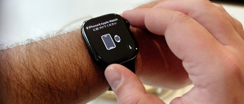 Die Person trägt die Apple Watch Series 11 am rechten Handgelenk, und nach dem Einschalten zeigt das Display in Englisch und einer weiteren Fremdsprache die Notwendigkeit an, die Smartwatch mit einem iPhone zu koppeln.