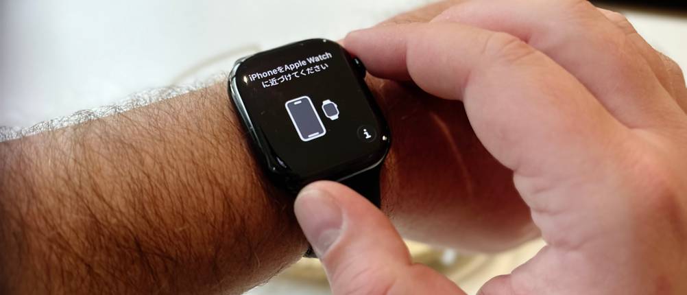 Die Person trägt die Apple Watch Series 11 am rechten Handgelenk, und nach dem Einschalten zeigt das Display in Englisch und einer weiteren Fremdsprache die Notwendigkeit an, die Smartwatch mit einem iPhone zu koppeln.