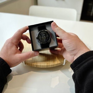 Eine Person hält die Schachtel mit der Garmin Fenix ​​8 in den Händen, und man kann das Uhrengehäuse und einen Teil des Armbands sehen.