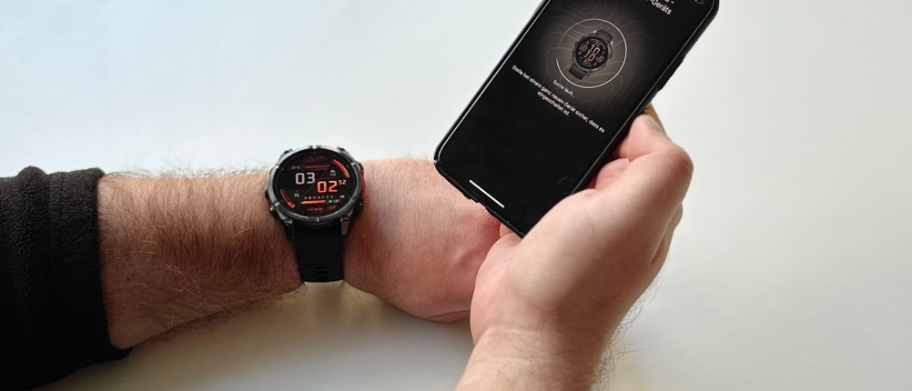 Die Person, die die Uhr am linken Handgelenk trägt und ihr Handy in der rechten Hand hält, koppelt die Smartwatch Fenix ​​8 mit der dazugehörigen App, die auf ihrem Handy installiert ist.