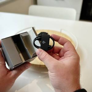 Die Person zeigt den Inhalt der Schachtel und hält das USB-Ladekabel in den Händen, das zur Garmin-Fenix-8-Smartwatch gehört.