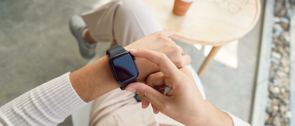 Eine Frau prüft ihre Smartwatch, die sie am linken Handgelenk trägt.