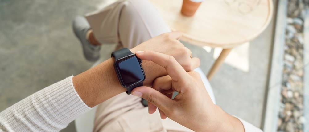 Eine Frau prüft ihre Smartwatch, die sie am linken Handgelenk trägt.