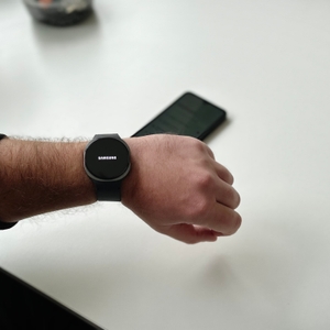 Die Person trägt eine Samsung-Galaxy-Watch-8-Smartwatch an ihrem linken Handgelenk, und der Markenname Samsung ist auf dem Display sichtbar.