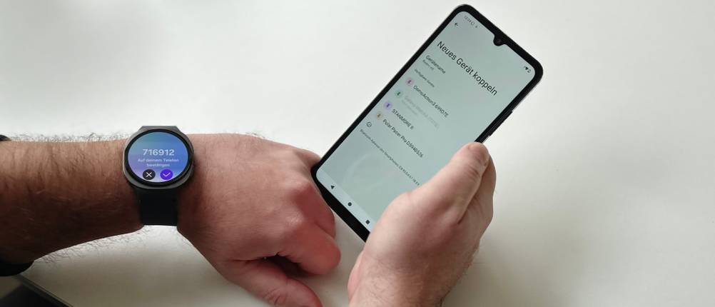 Die Person trägt die Samsung-Galaxy-Watch-8-Smartwatch am linken Handgelenk und hält das Smartphone in der rechten Hand, während sie Uhr und Smartphone koppelt.
