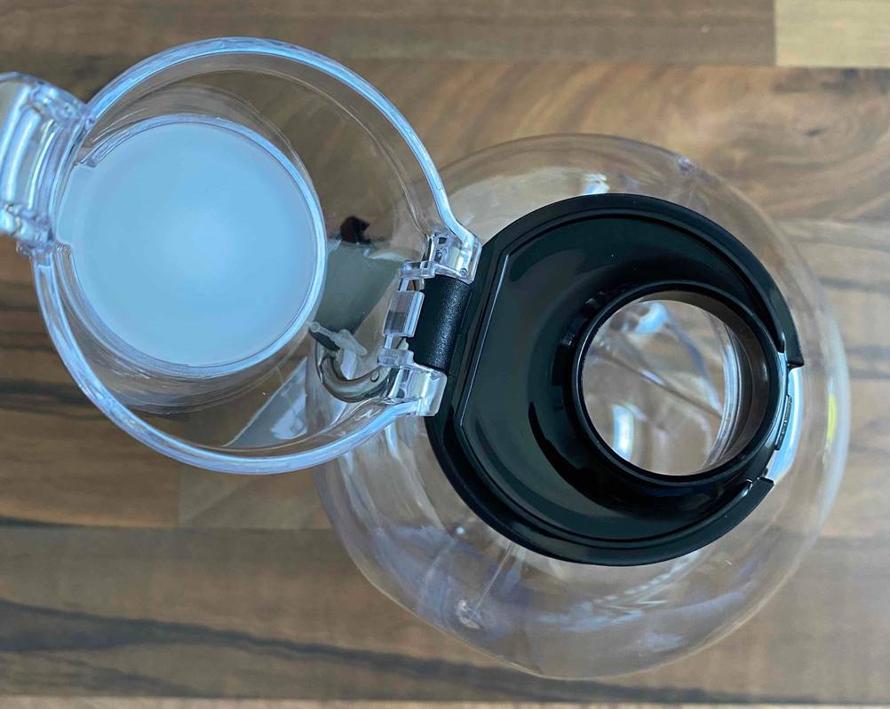 1,5-Liter-Trinkflasche im Test: Nahaufnahme der Verschlusskappe und der Trinköffnung eines transparenten Modells auf Holzuntergrund.