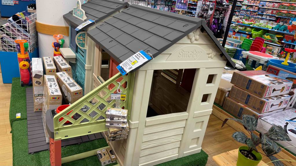 Das getestete Spielhaus mit externer Küche steht in einem Spielzeugladen auf einem grünen Kunstrasen.
