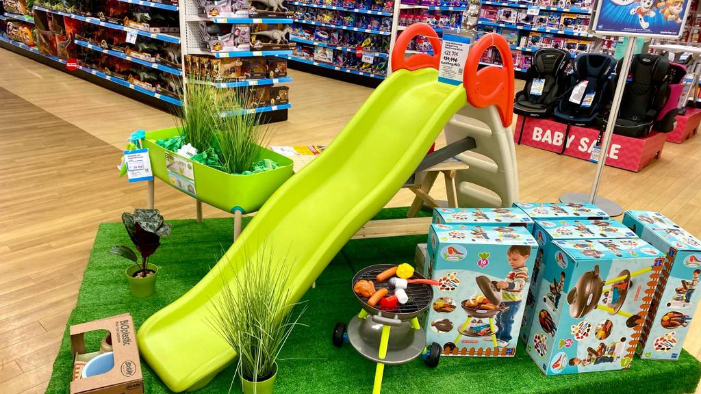 Gesamtansicht inklusive Preisschild einer Kinderrutsche im Test, die aus Kunststoff besteht und mit einer hellgrünen Rutsche, roten Griffen und einer beigefarbenen Treppe ausgestattet ist.