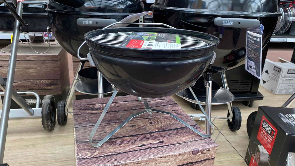 Im Test: Ein Kugelgrill von der Seite, der auf einem Holzpodest steht.