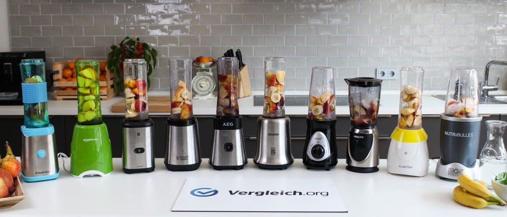 Verschiedene Smoothie-Maker mit enthaltenen Früchten stehen in einer Reihe