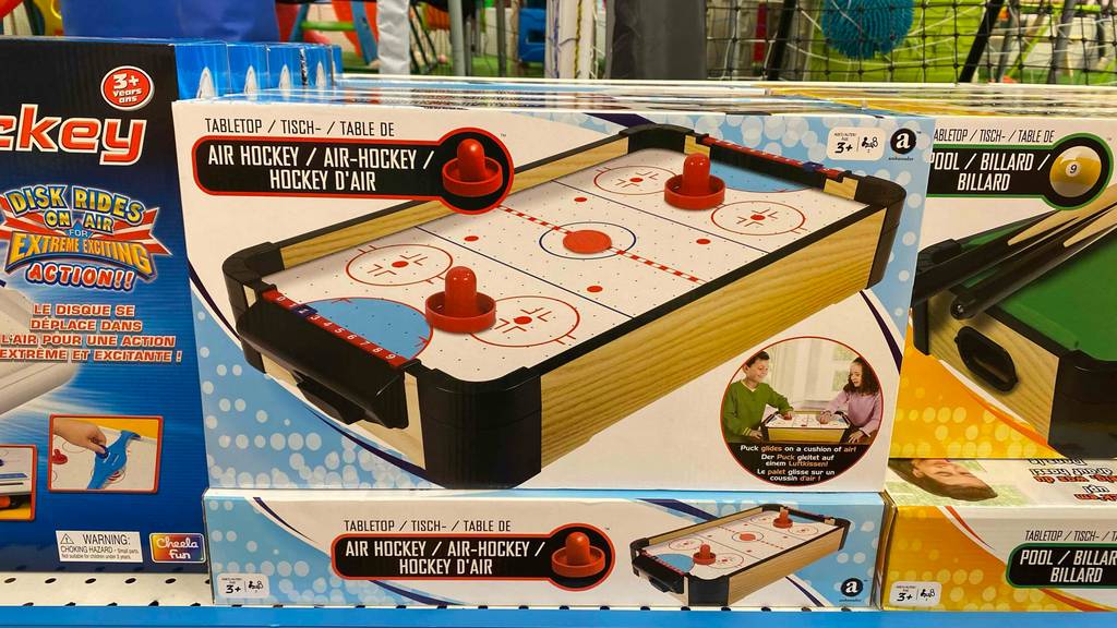 Air Hockey im Test: mehrere verpackte Geräte stehen gestapelt in einem Regal.