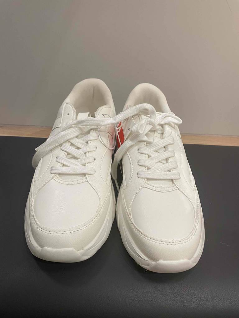Ein Paar Sneakers für Damen im Test von vorne auf einer dunklen Fläche.