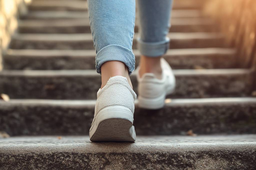 Damen-Sneaker-test: Eine Frau in Jeans und Weißen sneakern geht stufen hinauf. 