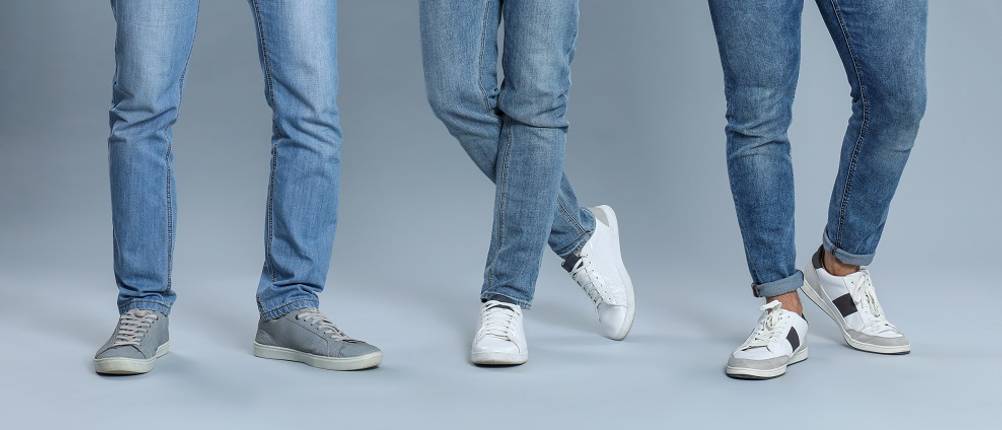 sneaker-herren-test: drei Männer mit Jeans und grauen und weißen Sneakern.