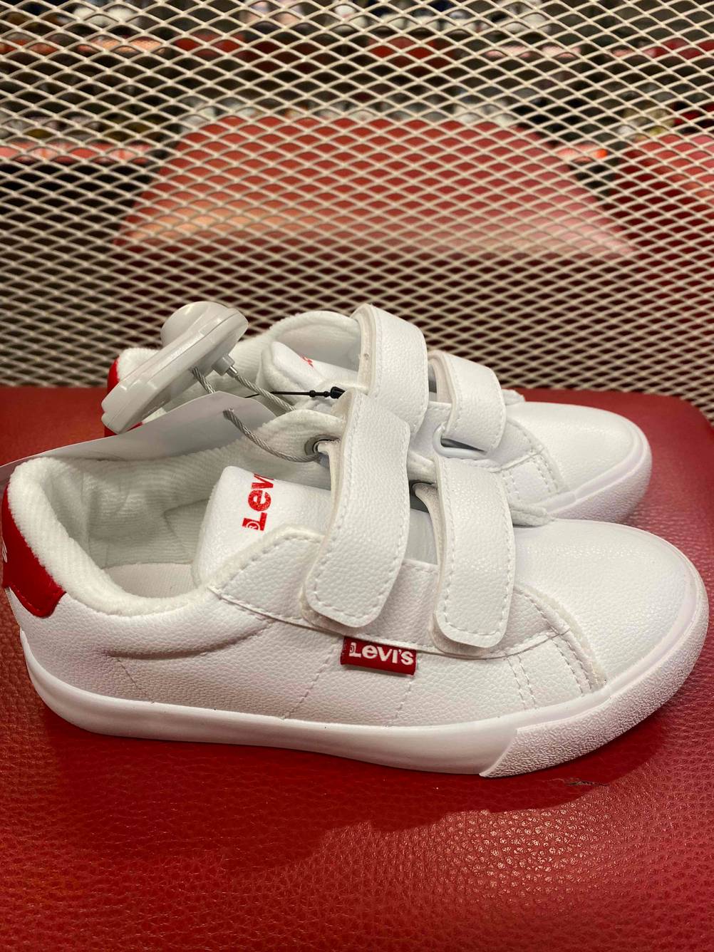 Ein Paar getestete Sneaker für Kinder von der Seite auf einer roten Fläche.