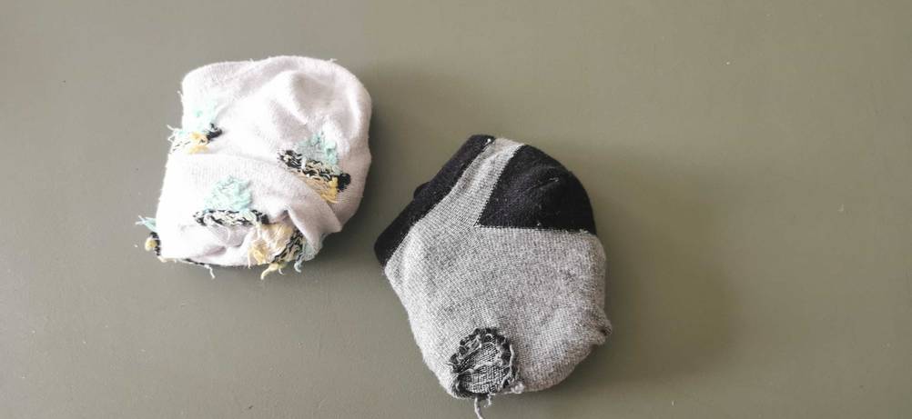 Zwei Paar getestete Sneaker-Socken liegen zusammengerollt auf einer grauen Oberfläche.