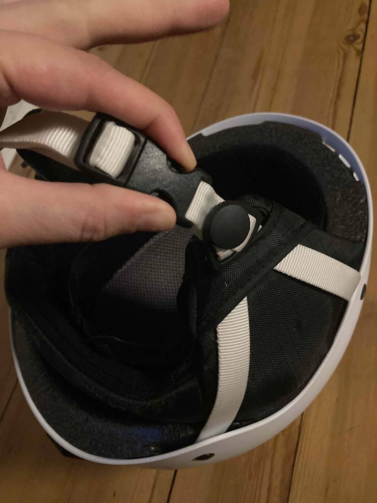 Eine Hand hält den Verschluss eines getesteten Snowboardhelms.
