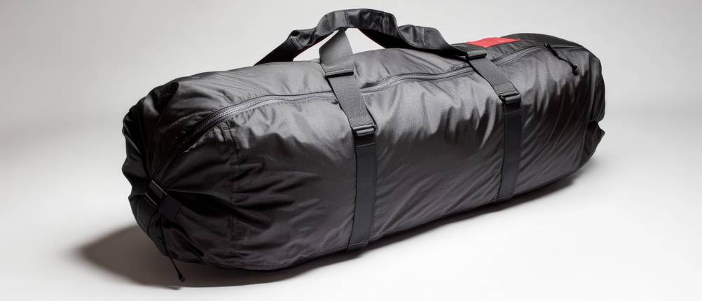 Snowboardtasche-Test: vollgepackte schwarze Snowboardtasche vor hellgrauem Hintergrund