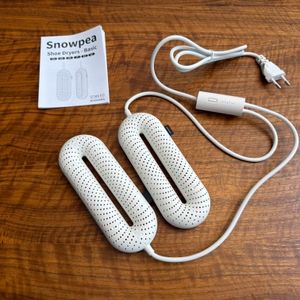 Der Snowpea-Schuhtrockner liegt neben der Anleitung auf einem Tisch