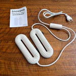 Der Snowpea-Schuhtrockner liegt neben der Anleitung auf einem Tisch