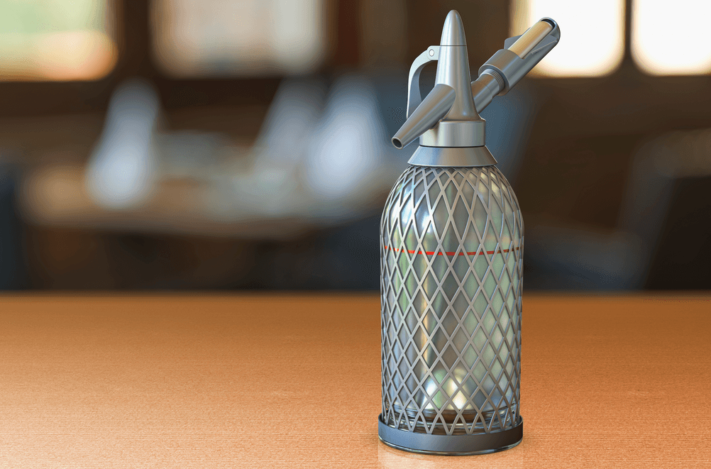 Soda-Siphon-Test: Vollaufnahme eines Glas-Soda-Siphons auf einer Holzfläche. 