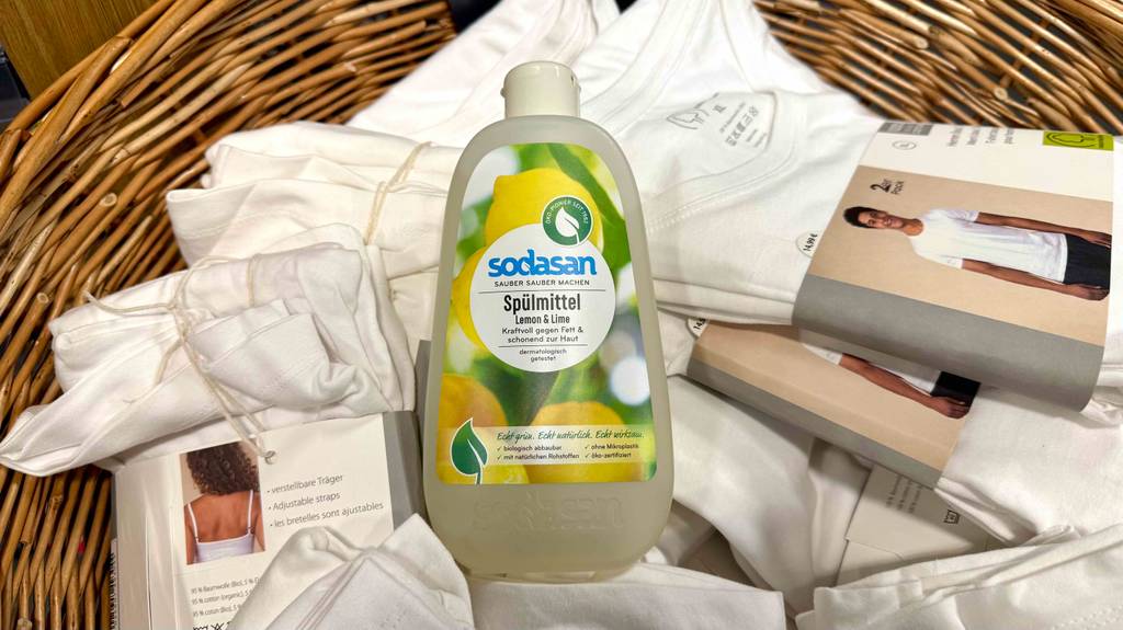 Im Test: Ein Öko-Spülmittel in der Kunststoffflasche liegt auf einem Berg Unterwäsche für Damen und Herren.