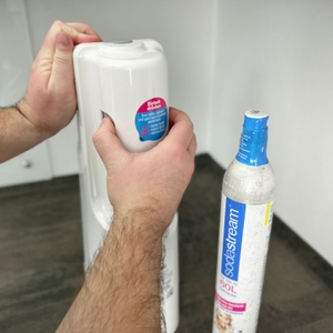 Eine Person entfernt die Rückwand des SodaStream Cool, um den CO₂-Zylinder zu wechseln.