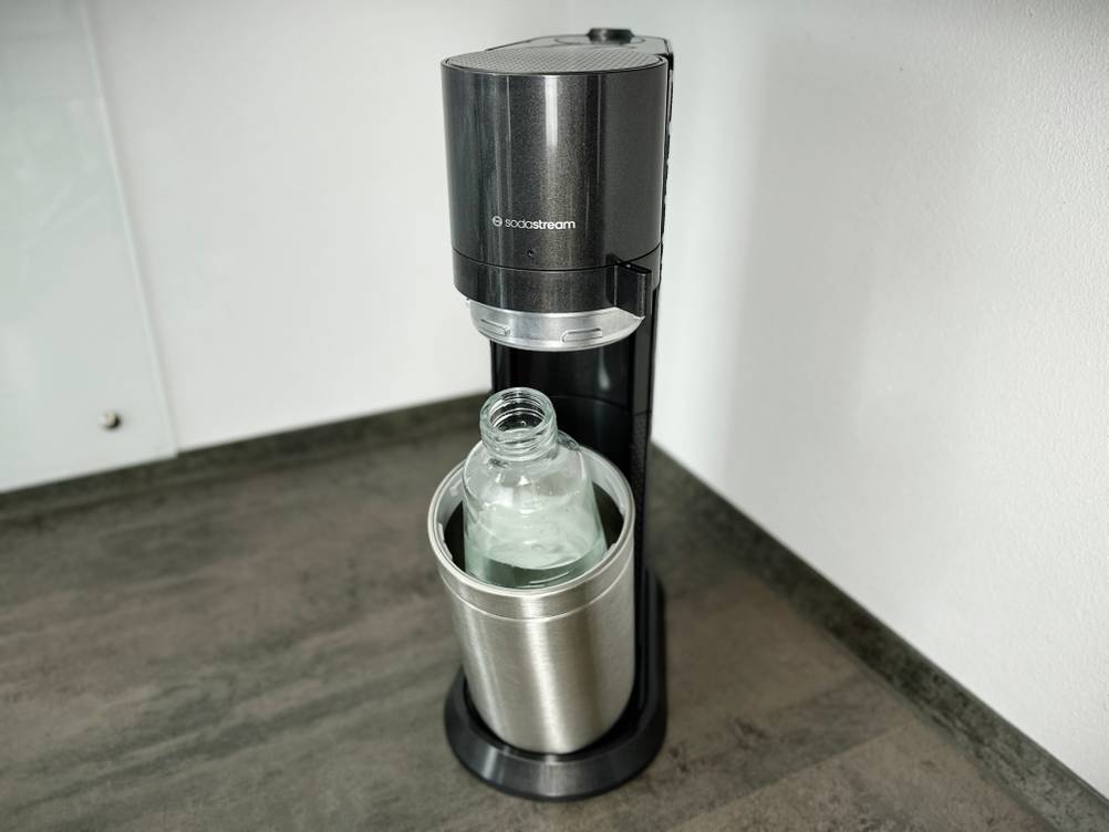 Eine Glasflasche mit Wasser steht im geöffneten SodaStream Duo Sprudler.