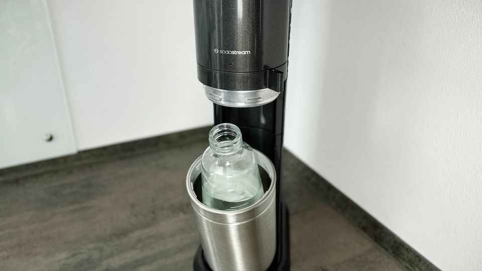 Eine Glasflasche mit Wasser steht im geöffneten SodaStream Duo Sprudler.