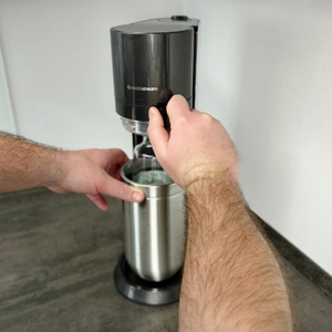 Eine Person verriegelt den Deckel des SodaStream Duo durch Herunterdrücken des oberen Teils.