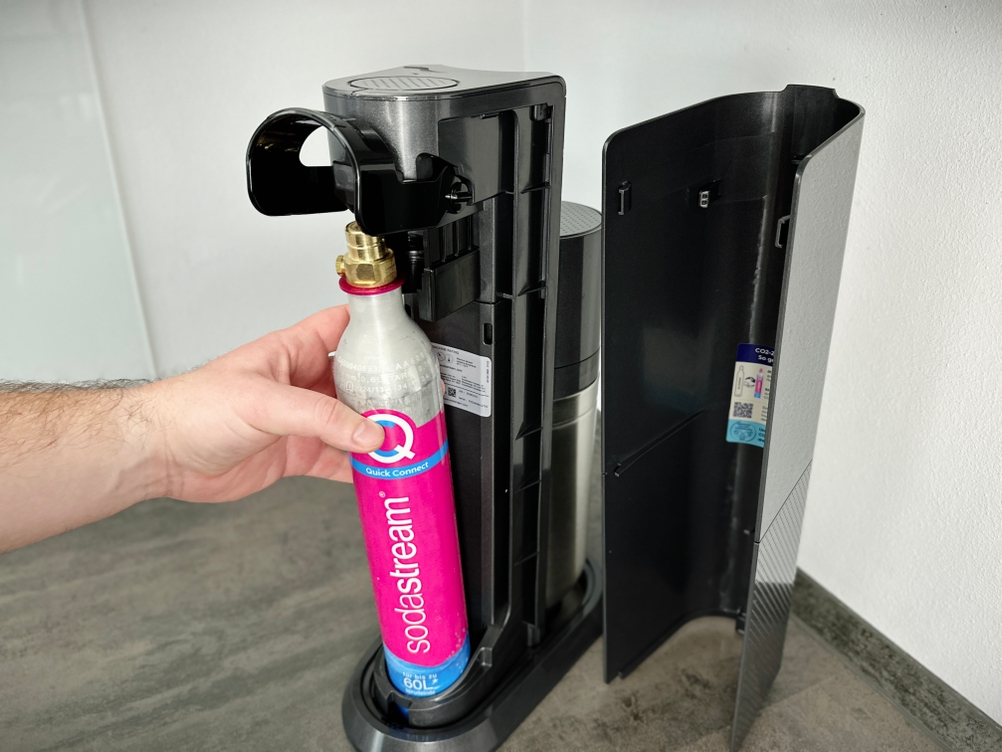 Eine Hand setzt einen SodaStream Quick-Connect-Zylinder in den Sprudler ein.