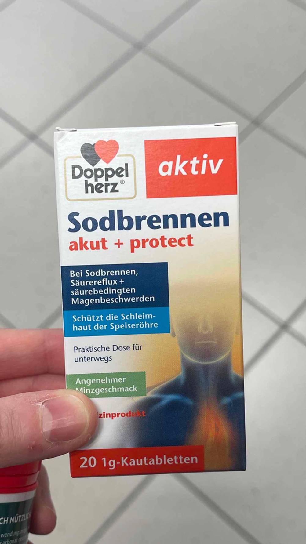 Eine Hand hält eine Packung der getesteten Sodbrennen-Tabletten hoch.