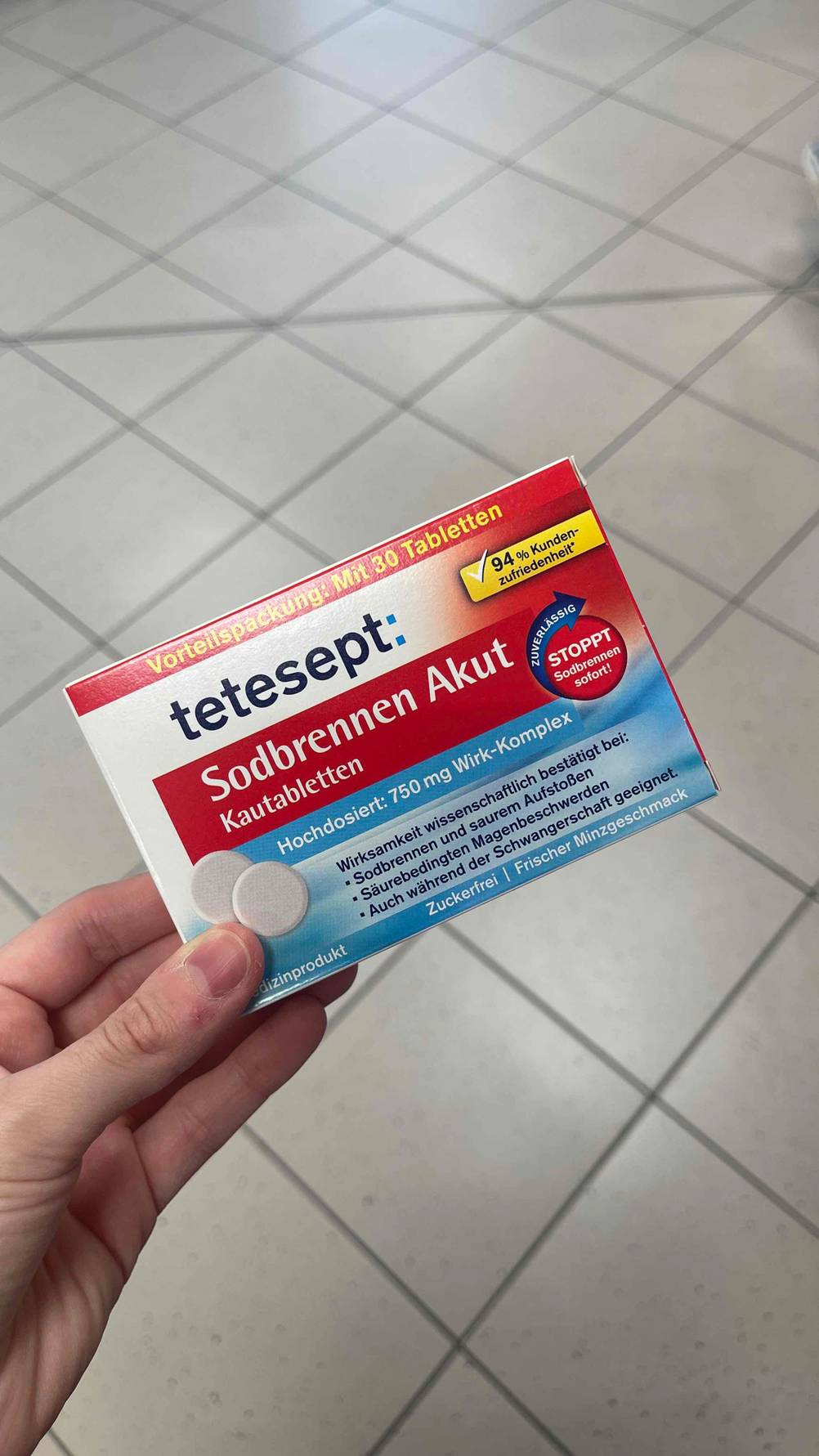 Die Packung der getesteten Sodbrennen-Tabletten von einer Hand gehalten.