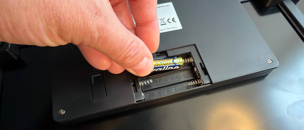 Eine Hand legt eine Batterie in die Soehnle Style Sense Safe 300.