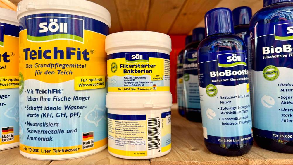 Zwei Packungen der getesteten Teichbakterien übereinander eine von vorne eine von hinten neben anderen Produkten in einem Verkaufsregal.