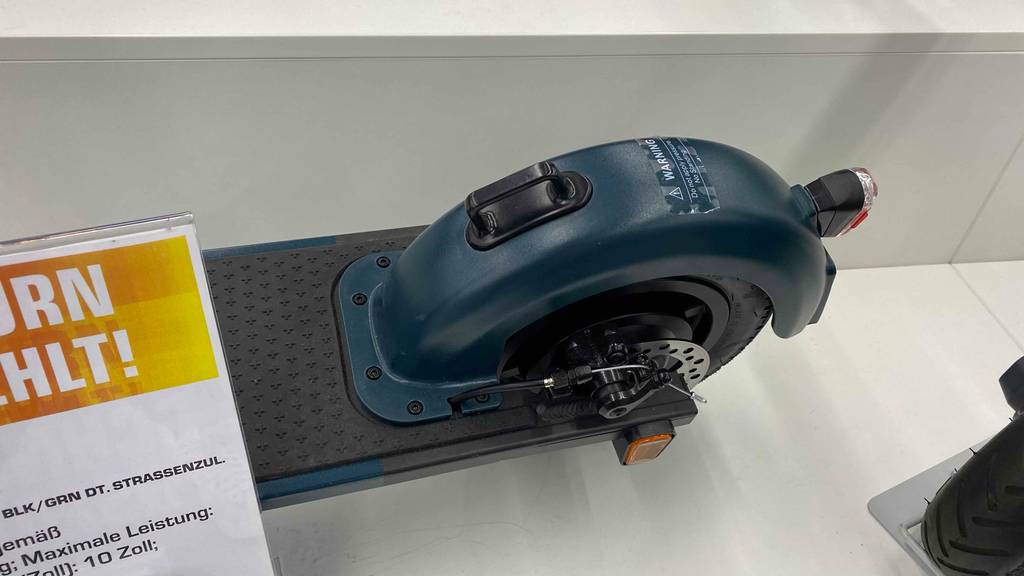 Hinterreifen im Detail eines getesteten E-Scooters mit 500 Watt, der auf weißem Boden steht.