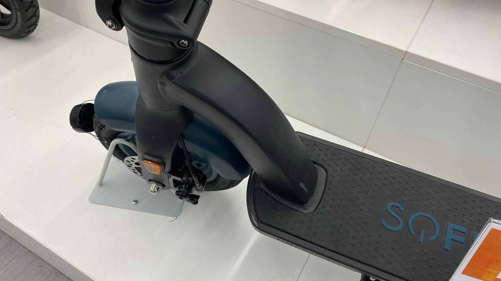 Vorderreifen und Trittfläche im Detail eines getesteten E-Scooters mit 500 Watt, der auf weißem Boden steht.