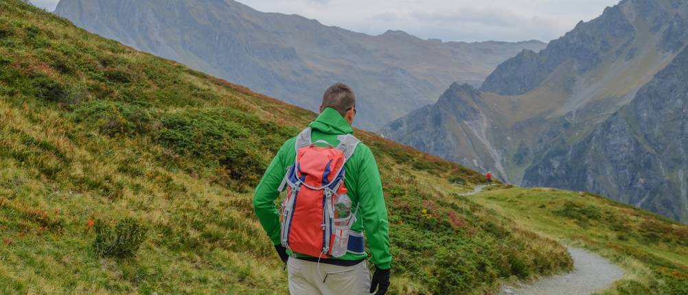 Softshelljacke-Damen-Test: Ein Wanderer in der Natur mit einem Rucksack und einer Softshelljacke.