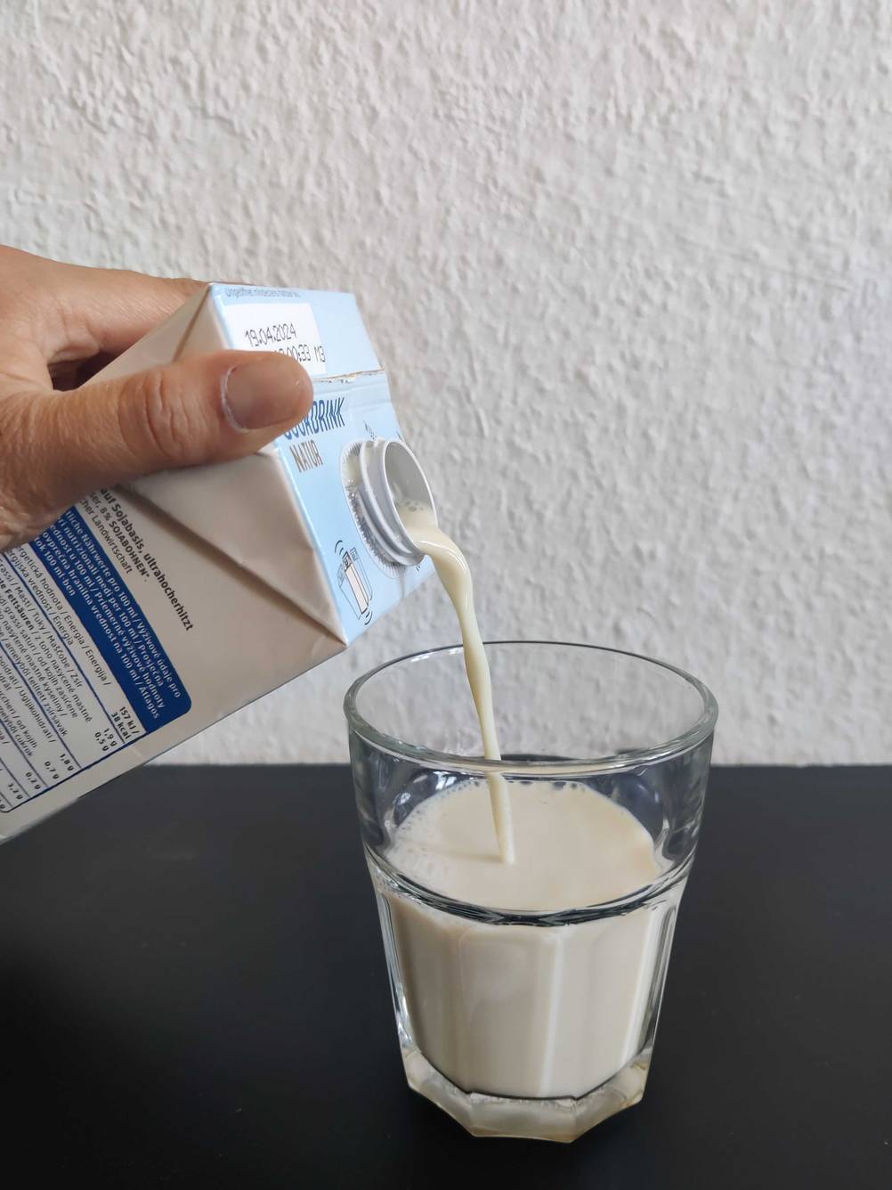 Sojadrink getestet: Eine Hand schenkt ein Glas Sojadrink ein.