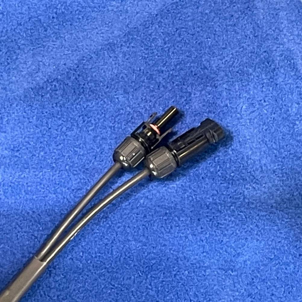 Die Stecker der getesteten Solar-Jalousien liegen auf einem blauen Untergrund.