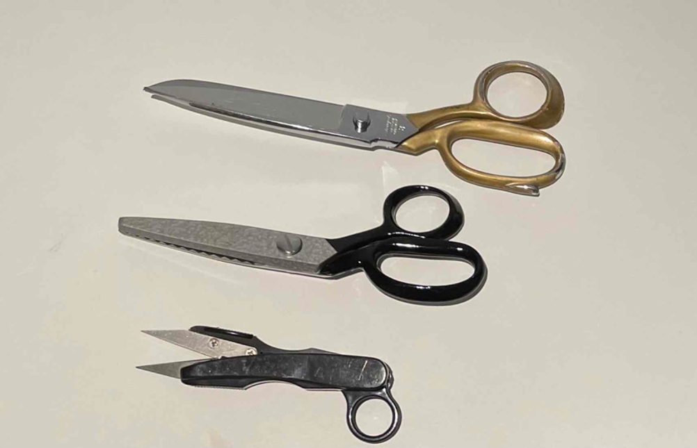 Schneiderschere im Test: drei verschiedene Scheren liegen übereinander auf weißer Fläche.