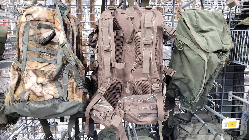 Ein getesteter Rucksack mit 45 Liter hängt mit den Trägern nach vorn in einem Gitterregal zwischen zwei anderen Rucksäcken.